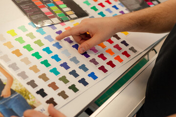 Cropped man hand choosing samples catalog multicolor advertising T-shirts palette film membrane....