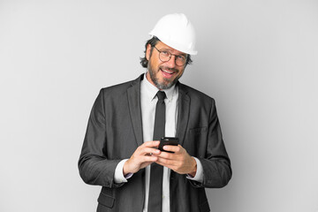 Young architect man with helmet over isolated background surprised and sending a message