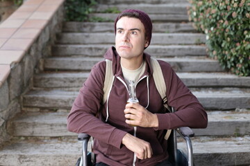 Depressed man on a wheelchair holding beer bottle