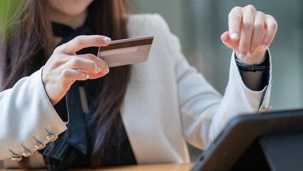 Close-up woman's hands holding a credit card and using tablet pc.