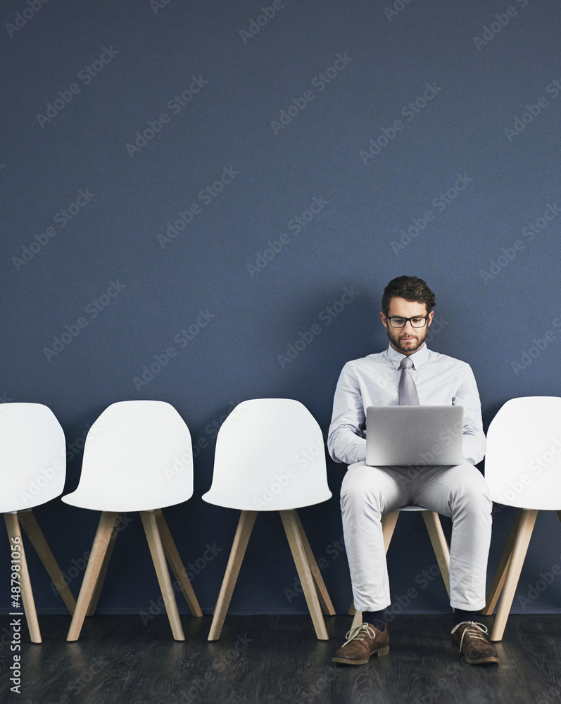 Poster last minute research before the interview. studio shot of a young businessman using a laptop while w