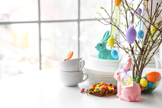 Nest with Easter eggs, rabbits and dishware on dining table