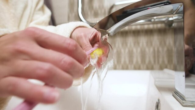 Women's hands in the bathroom washes a splint from bruxism. Preventive regular cleaning of the aligner to correct the bite and align the teeth