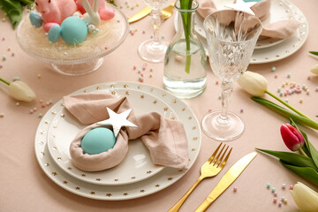 Stylish table setting for Easter celebration with tulip flowers on light background