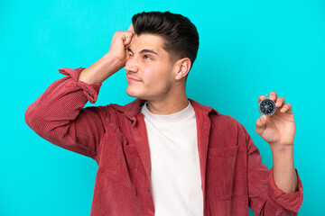 Young handsome caucasian man holding compass having doubts and with confuse face expression