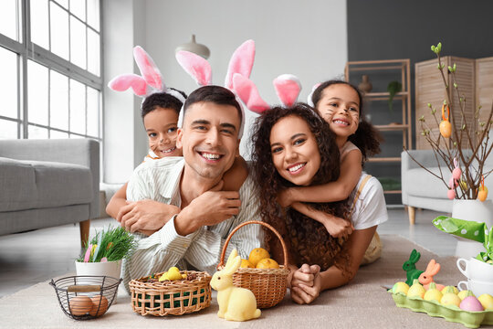 Happy parents with their little children in bunny ears at home