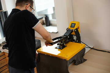 Man worker glasses back using heat thermal textile application transfer machine. Printing...