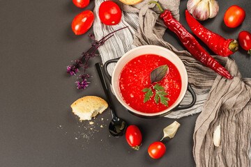 Vegan food, spicy tomato gazpacho soup with toasts, ripe vegetables, and fresh basil herbs