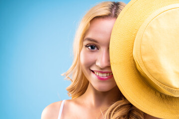 Young beautiful blond woman is covering her face with yellow hat. Ready for beach sea holiday...