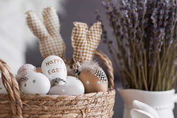 Beautiful postcard. A wicker basket with Easter eggs, lavender and rabbits in close-up. Provence. The concept of the bright Easter holiday 2022.