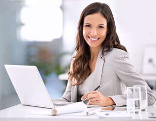 Shes made it. Shot of an attractive businesswoman sitting at her desk in an office.