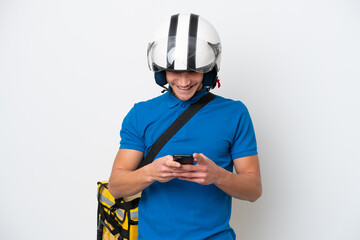 Young caucasian man with thermal backpack isolated on white background sending a message with the mobile