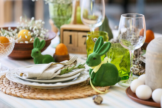 Plates with napkin, cutlery and eucalyptus branch on table served for Easter celebration