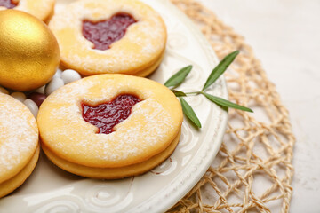 Plate with delicious Easter cookies on light background