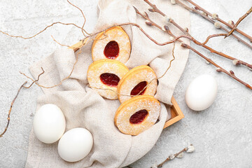 Box with delicious Easter cookies and eggs on light background