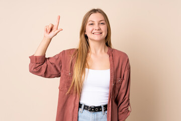 Teenager Ukrainian girl isolated on beige background pointing up a great idea