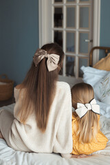 Portrait from behind of loving beautiful young mother and little daughter with long gorgeous hair...
