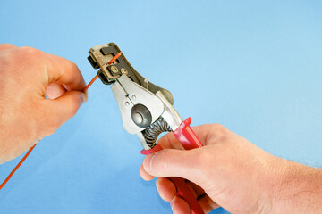 An electrician removes insulation from a copper wire. Working with the tool. Stripper work close-up.