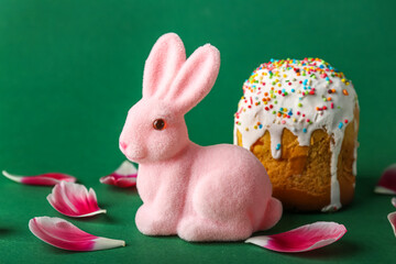 Cute Easter bunny with cake and tulip petals on green background