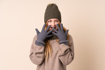 Teenager Ukrainian girl with winter hat isolated on beige background with surprise facial expression