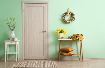 Interior of room with beautiful Easter decor and wooden door near color wall - Powered by Adobe