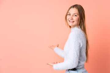 Teenager Ukrainian girl isolated on pink background extending hands to the side for inviting to come