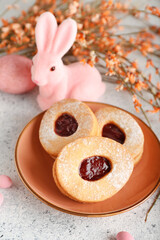 Plate with tasty Easter cookies in shape of eggs on light background