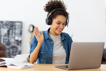 Portrait African American female student in headphones using laptop computer having video call...