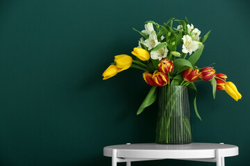 Vase with flowers on table near color wall