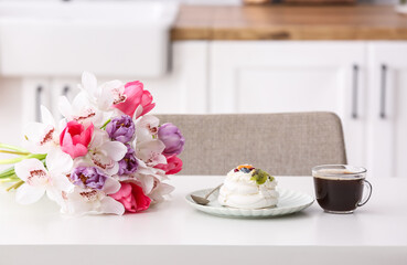 Bouquet of flowers, meringue cake and cup of coffee on dining table