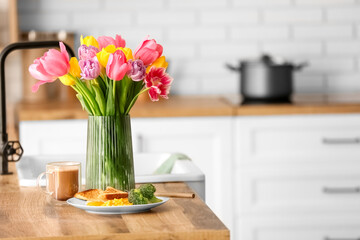 Vase with tulips and breakfast on kitchen counter