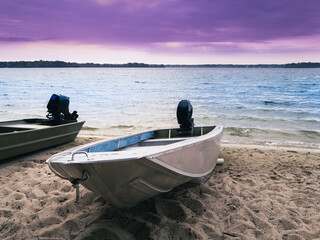 Two motorboats moored on the beach. Dramatic purple cloudscape at sea.