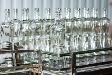 Empty glass bottles on the conveyor. Factory for bottling alcoholic beverages. Production and...