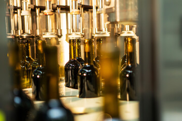 Unlabeled glass bottles in bottling machine at modern winery - 487988480