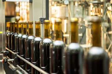 Unlabeled glass bottles in bottling machine at modern winery - 487988484