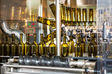Unlabeled glass bottles in bottling machine at modern winery