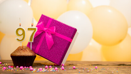 Happy birthday with a pink gift box for a 97 year old woman. Beautiful birthday card with cupcake and burning candle number ninety seven