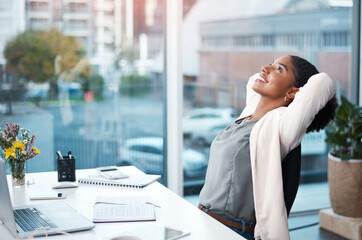 More success, less stress. Shot of a young businesswoman relaxing at her desk in a modern office.