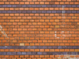Orange clinker wall background texture with different stones. Dirty weathered surface of an old rough building exterior. Pattern of a fine facade structure with different colored bricks.