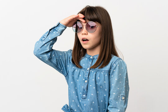 Little girl with sunglasses isolated on white background doing surprise gesture while looking to the side