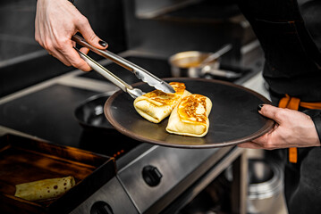 chef hand cooking Thin pancakes crepe rolls with ground meat in pan at a restaurant kitchen