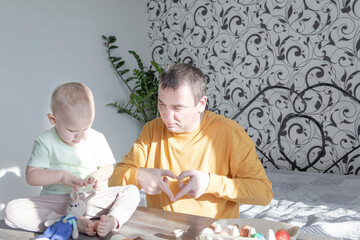 A dad celebrates Easter with his young son. They beat eggs, eat eggs and have breakfast. Dad teaches the child.