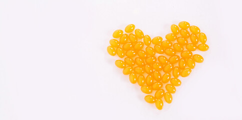 Vitamin D and Omega 3 fish oil capsules supplement in a heart-shaped plate on white background....
