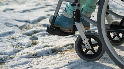 Close-up of legs of woman in wheelchair in winter outdoors. 