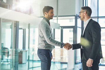 Youve been doing exceptionally well. Shot of two businessmen shaking hands together in an office.