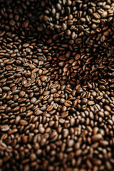 braun geröstete Kaffeebohnen in Nahaufnahme in einer Kaffee Rösterei vertikal