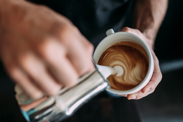 Fototapeta na wymiar Barista macht ein Herz aus Milchschaum in einer Kaffee Rösterei