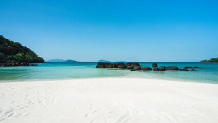 Fototapeta na wymiar Peaceful white sand beach with iconic black volcanic rock of Koh Kham Island and crystal clear turquoise water. Near Koh Mak Island, Trat Province, Thailand.
