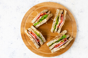 sandwich with ham cheese tomatoes lettuce onions on cutting board. Classic club sandwich with whole grain bread