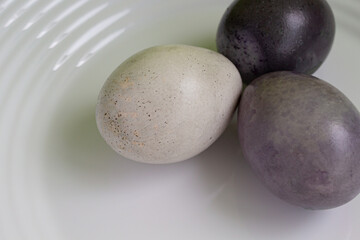 Easter painted eggs on a white plate close-up view from above.
